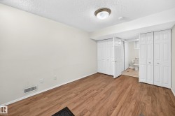 Room featuring wood-finish flooring, light-toned walls, and a ceiling-mounted light fixture - 