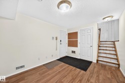Entry area featuring wood-finish flooring, white doors, and a wood staircase with white risers - 