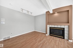 Living area featuring wood-finish flooring and a fireplace with a tiled surround - 