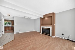 Living area featuring wood-finish flooring, a built-in fireplace with a tiled hearth, an integrated niche with accent lighting, and track lighting - 
