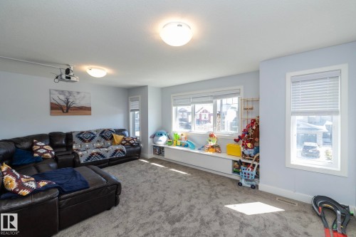 Spacious room featuring light blue walls, gray carpet flooring, and multiple windows with white blinds - 2016 Redtail Common, Edmonton, AB 
