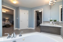 Bathroom featuring a corner soaking tub with chrome fixtures, a single vanity with a light-toned countertop and undermount sink, and tile flooring - 