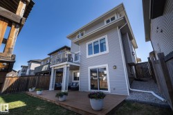 Rear exterior with a wooden deck, manicured lawn, and privacy fencing - 