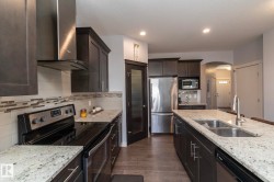 Modern kitchen featuring dark wood cabinetry and light-toned granite countertops - 