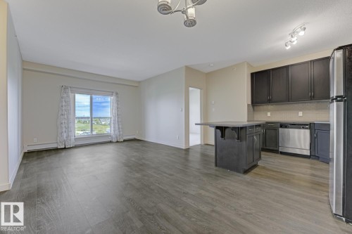 Open-concept living area featuring wood-finish flooring and a large window - 450 11517 Ellerslie Road, Edmonton, AB 
