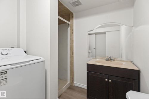 Corner vanity with a light-toned countertop, integrated sink, and an arched mirror - 156 Lee Ridge Road, Edmonton, AB - Indoor Photo Showing Bathroom