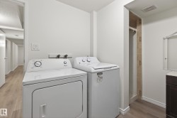 Dedicated laundry area featuring a white washing machine and dryer, light wood-finish flooring, and white walls - 