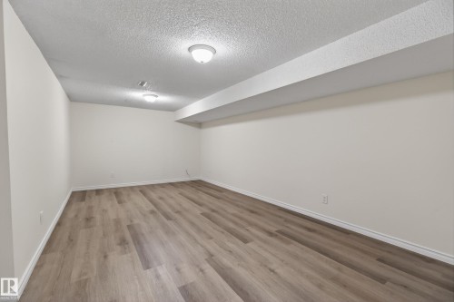 Spacious room featuring wood-finish flooring, light-colored walls, and a textured ceiling with flush-mount lighting fixtures - 156 Lee Ridge Road, Edmonton, AB - Indoor Photo Showing Other Room