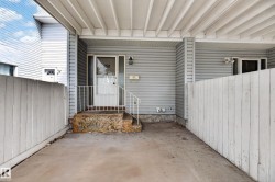 Covered entry with concrete flooring and light gray siding - 