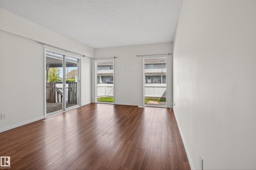 Spacious room with wood-finish flooring, white walls, and a textured white ceiling - 156 Lee Ridge Road, Edmonton, AB - Indoor