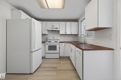 Kitchen featuring white cabinetry, wood-finish countertops, and light wood-finish flooring - 