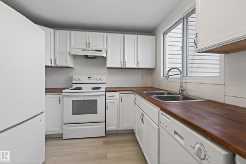 Kitchen featuring white cabinetry, wood-finish countertops, stainless steel sink, and light wood-finish flooring - 156 Lee Ridge Road, Edmonton, AB - Indoor Photo Showing Kitchen With Double Sink