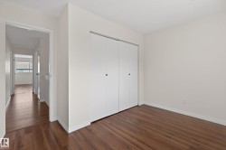 Room featuring wood-finish flooring, white walls, and a large bi-fold closet - 