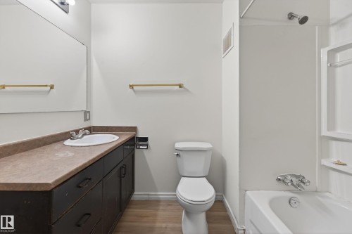 Full bathroom featuring a single vanity with dark cabinetry and a light-colored countertop, a white toilet, and a combination shower-tub with a silver showerhead and faucet - 156 Lee Ridge Road, Edmonton, AB - Indoor Photo Showing Bathroom