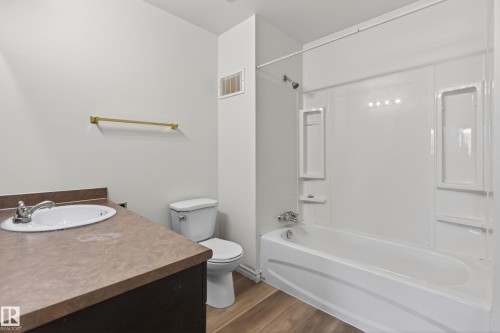 Bathroom featuring a white porcelain toilet, a vanity with a brown countertop and an integrated sink, a gold-toned towel bar, and wood-finish flooring - 156 Lee Ridge Road, Edmonton, AB - Indoor Photo Showing Bathroom
