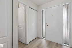 Entryway featuring a white main door with two fluted glass sidelights, complemented by wood-finish flooring - 