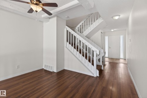 Open-concept interior featuring wood-finish flooring throughout, a multi-level staircase with white balusters, and a contemporary ceiling fan with integrated lighting - 156 Lee Ridge Road, Edmonton, AB - Indoor Photo Showing Other Room