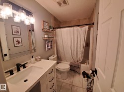 White vanity with a single basin sink and matte black faucet, framed mirror, and a wall-mounted light fixture featuring four clear glass shades - 