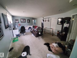 Carpeted room featuring light blue walls, recessed lighting, and a white paneled door - 