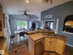 Kitchen featuring light wood-finish cabinetry, a double basin stainless steel sink, and wood-finish flooring - 