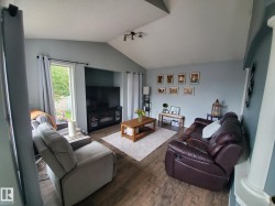 Living area featuring vaulted ceilings, wood-finish flooring, a built-in electric fireplace, and a large sliding glass door - 