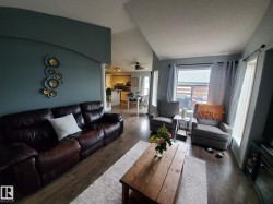 Living area featuring wood-finish flooring, vaulted ceilings, and an arched wall opening - 