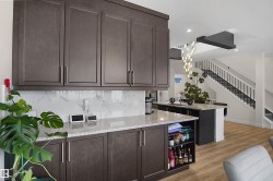 Kitchen featuring dark wood-finish cabinetry, light speckled countertops, and a white marble-patterned backsplash - 
