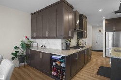 Expansive kitchen featuring wood-finish flooring, dark wood cabinetry, and light-toned countertops - 