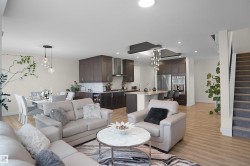 Open-concept living space featuring wood-finish flooring, recessed lighting, a modern kitchen with dark cabinetry, and a dining area with pendant lighting - 