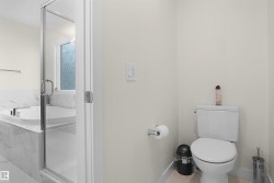 Bathroom featuring a white toilet, toilet paper holder, and light-colored walls - 