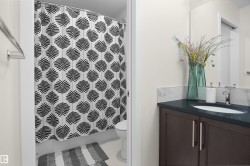 Bathroom featuring a dark wood-finish vanity with a dark countertop and integrated sink, a large wall-mounted mirror, and a full-size toilet - 