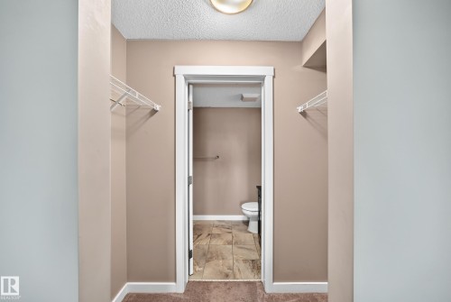 Hallway with built-in wire shelving and a doorway leading to a room with tiled flooring and a toilet - 308 18126 77 Street, Edmonton, AB 