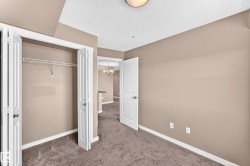 Carpeted room featuring a double bi-fold closet with shelving, neutral wall paint, white trim, and a semi-flush ceiling light - 