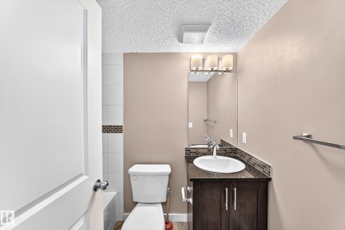 Bathroom featuring a dark wood-finish vanity with a white oval sink and a dark countertop - 308 18126 77 Street, Edmonton, AB 