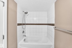 Bathtub and shower combination featuring white subway tile, a decorative mosaic tile accent band, and chrome fixtures - 