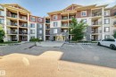 Multi-story residential building featuring a stone and siding exterior, multiple private balconies with black railings, and a prominent main entrance - 308 18126 77 Street, Edmonton, AB 