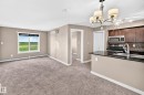 Open-concept living space featuring a window with expansive outdoor scenery, a split-system air conditioning unit, and plush carpet flooring - 308 18126 77 Street, Edmonton, AB 