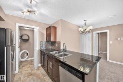 Kitchen island with dark countertop, stainless steel double basin sink, and integrated dishwasher - 