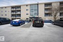 Multi-story building featuring light-colored siding, multiple balconies with dark railings, and a central glass entrance - 107, 2624 Millwoods Road East Nw, Edmonton, AB  - Outdoor 