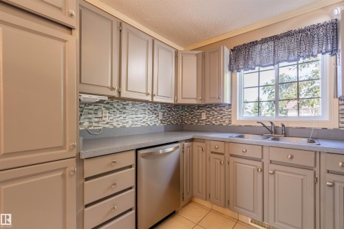 Kitchen featuring light gray cabinetry, a mosaic tile backsplash, a double basin stainless steel sink, and a stainless steel dishwasher - 3 Glenforest Crescent, Stony Plain, AB 