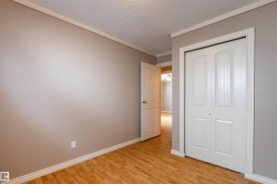 Room featuring wood-finish flooring, neutral wall paint, white baseboards, and crown molding - 