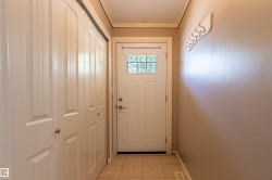 Entryway featuring a paneled door with decorative glass, beige floor tiles, and bi-fold closet doors - 