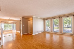 Spacious interior featuring wood-finish flooring throughout, multiple large windows providing abundant illumination, crown molding, and a visible chandelier in the dining area - 