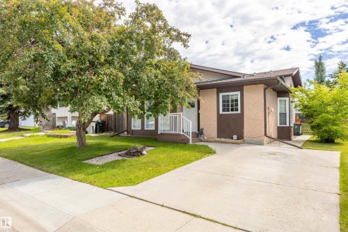 Contemporary exterior featuring two-tone stucco siding, white window frames, an angled roofline, and a concrete driveway - 3 Glenforest Crescent, Stony Plain, AB 