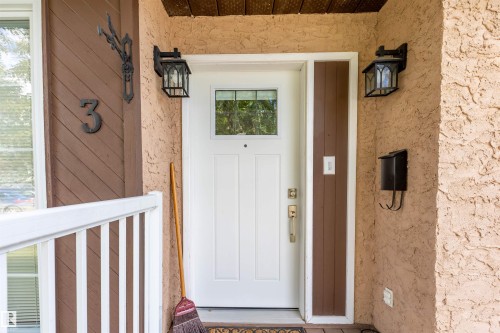 Entryway featuring a white paneled door with glass insert, textured stucco siding, and decorative wall lanterns - 3 Glenforest Crescent, Stony Plain, AB 