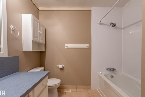 Bathroom featuring a white bathtub with an integrated shower, a toilet, and a vanity with a laminate countertop - 3 Glenforest Crescent, Stony Plain, AB 