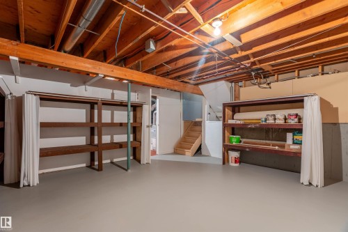 Unfinished basement space featuring exposed wood joists and ductwork, painted concrete flooring, and built-in wood shelving - 3 Glenforest Crescent, Stony Plain, AB 