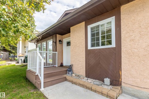 Exterior featuring a stucco finish, a covered entry porch with wood-finish decking, and white railings - 3 Glenforest Crescent, Stony Plain, AB 