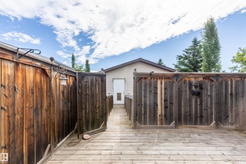 Expansive outdoor decking features a wood-paneled privacy fence and a built-in outdoor light fixture - 3 Glenforest Crescent, Stony Plain, AB 