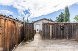 Expansive outdoor decking features a wood-paneled privacy fence and a built-in outdoor light fixture - 
